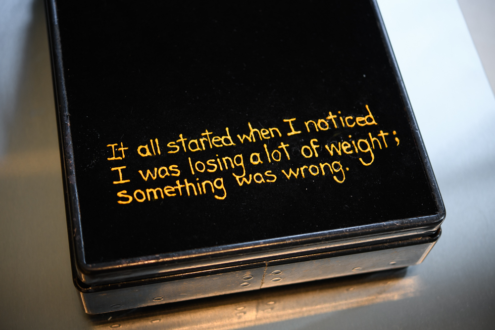 A black rectangular object with yellow handwritten text that reads: It all started when I noticed I was losing a lot of weight; something was wrong.